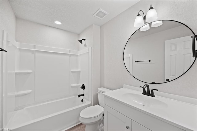 full bathroom with wood-type flooring, a textured ceiling,  shower combination, toilet, and vanity