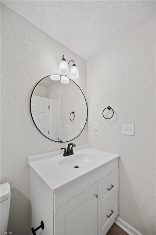 bathroom featuring vanity, toilet, and a textured ceiling