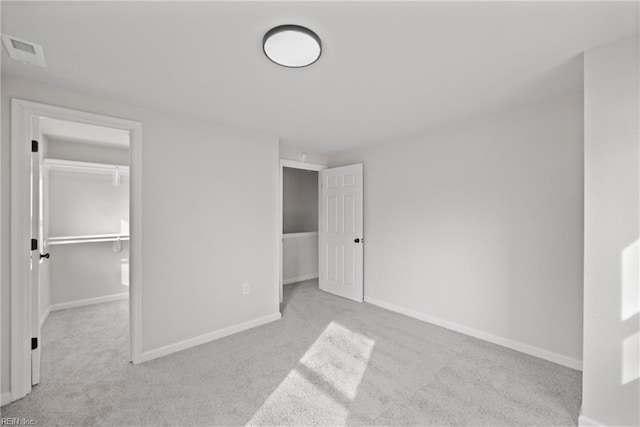 unfurnished bedroom with a walk in closet, light carpet, and a closet