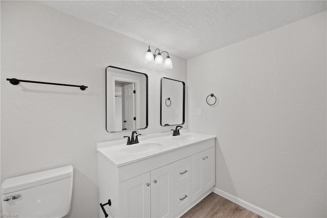 bathroom featuring vanity, wood-type flooring, a textured ceiling, and toilet