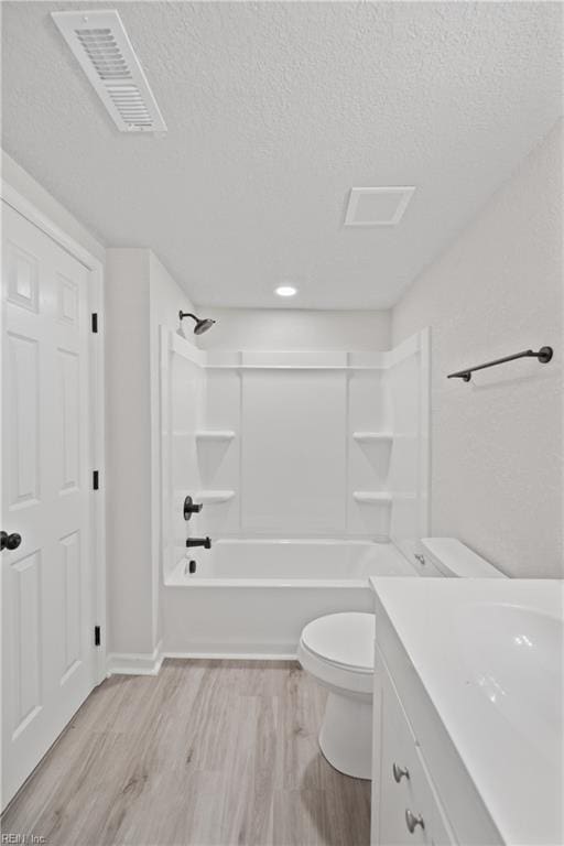 full bathroom featuring hardwood / wood-style floors, vanity, toilet, a textured ceiling, and shower / bathtub combination