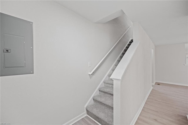 stairs featuring wood-type flooring and electric panel