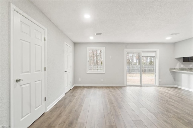 spare room with a textured ceiling and light wood-type flooring