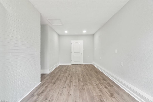 spare room featuring light wood-type flooring and brick wall