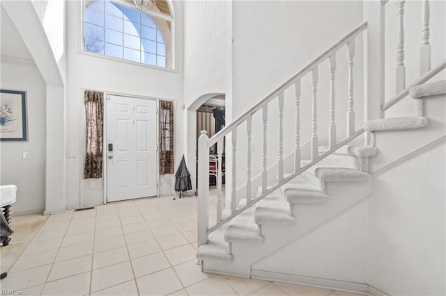 entryway with light tile patterned floors and a high ceiling