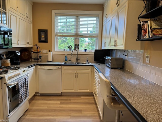 kitchen with tasteful backsplash, sink, white appliances, and light hardwood / wood-style flooring