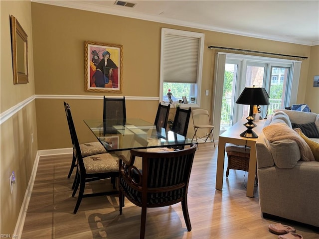 dining room featuring crown molding and light hardwood / wood-style flooring