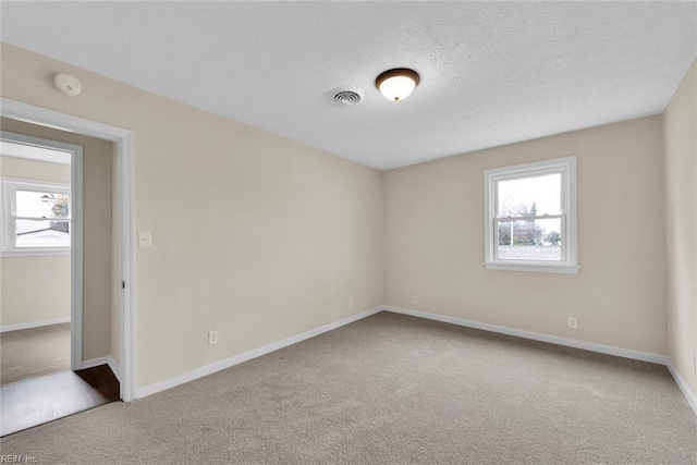 carpeted spare room featuring a textured ceiling