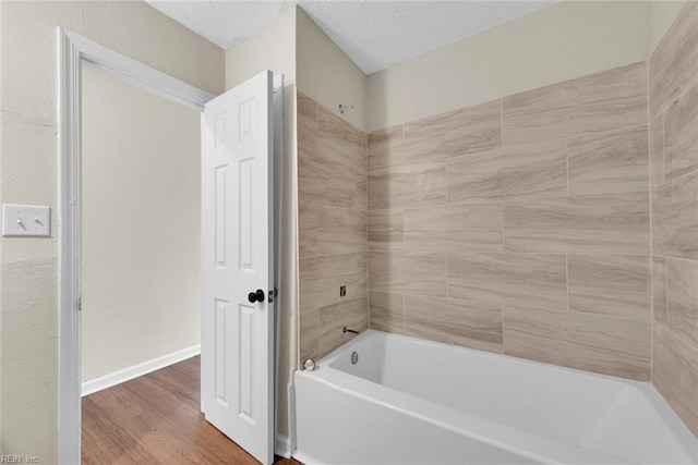 bathroom with hardwood / wood-style flooring and tiled shower / bath