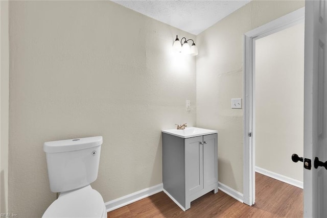 bathroom featuring hardwood / wood-style floors, vanity, toilet, and a textured ceiling