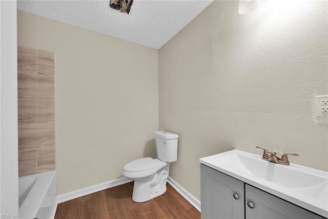 bathroom with hardwood / wood-style floors, vanity, a washtub, toilet, and a textured ceiling