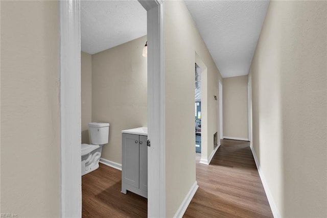 corridor with light wood-type flooring and a textured ceiling