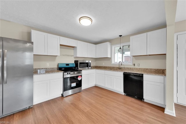 kitchen with stainless steel appliances, sink, light hardwood / wood-style flooring, white cabinets, and hanging light fixtures