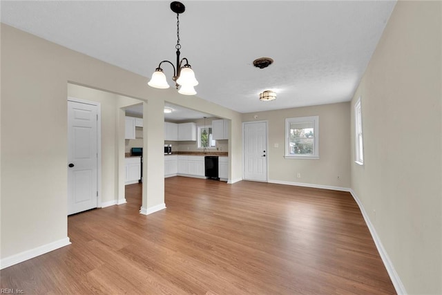 unfurnished living room featuring a notable chandelier and light wood-type flooring