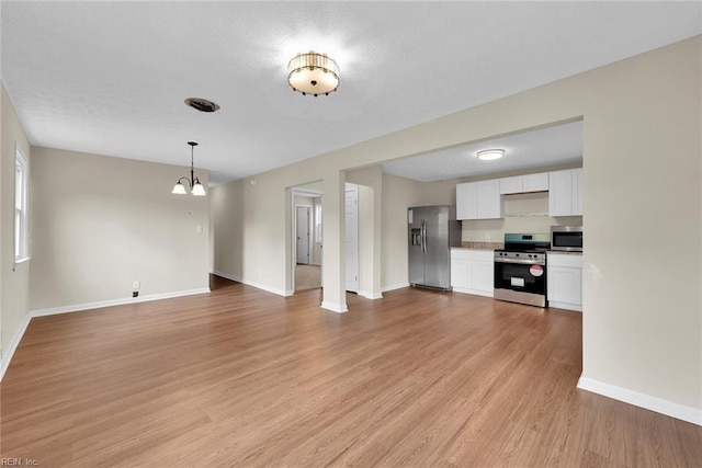 unfurnished living room featuring light hardwood / wood-style flooring and a notable chandelier