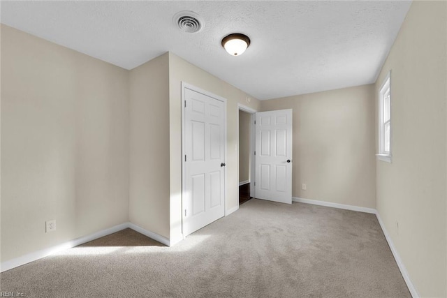 spare room with light colored carpet and a textured ceiling