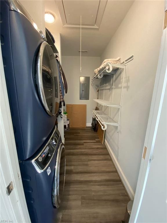 clothes washing area with stacked washing maching and dryer, dark hardwood / wood-style flooring, and electric panel