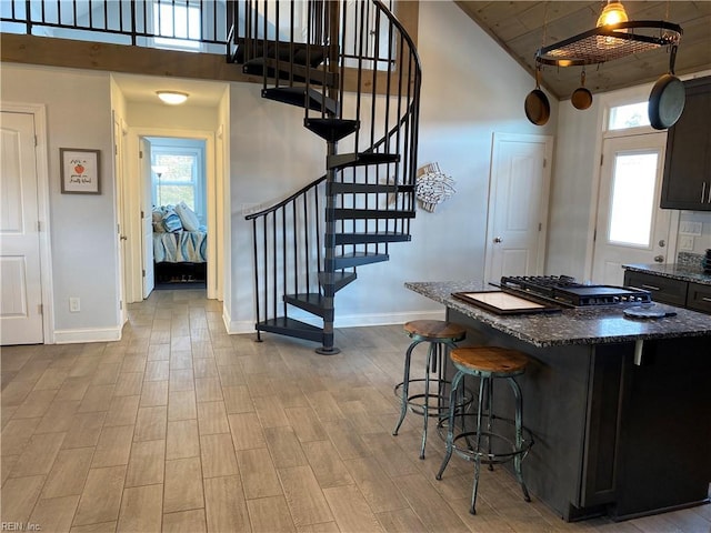 kitchen with dark stone countertops, a center island, a high ceiling, a breakfast bar area, and range