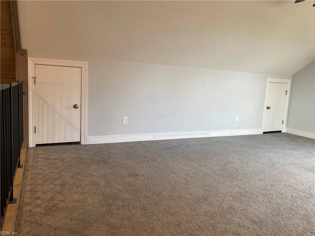 unfurnished room featuring lofted ceiling and dark colored carpet