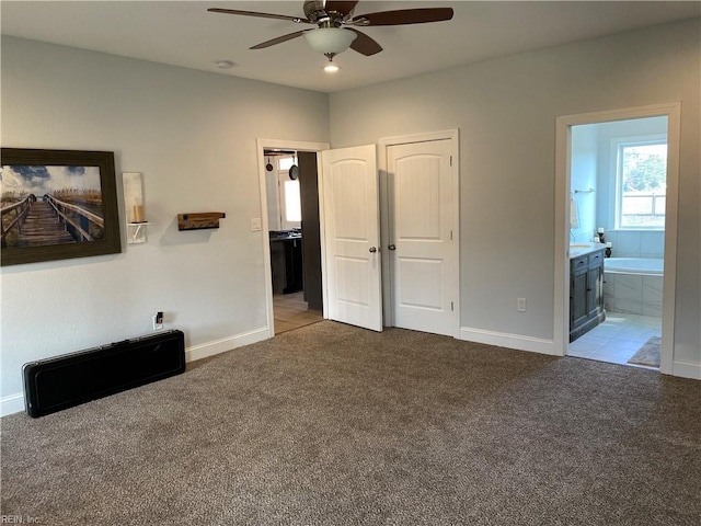 unfurnished bedroom with ceiling fan, light colored carpet, and ensuite bath