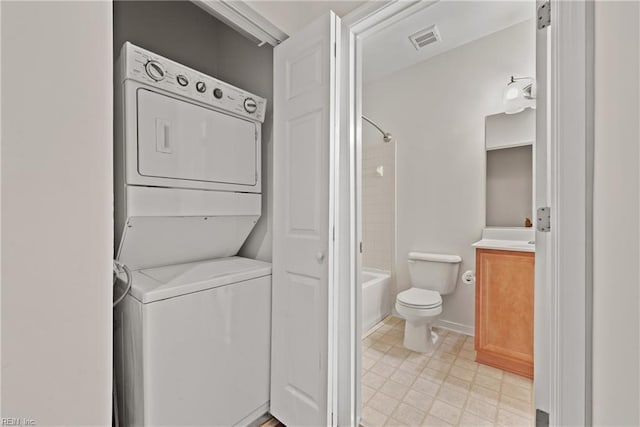 bathroom featuring stacked washer and dryer, visible vents, toilet,  shower combination, and vanity