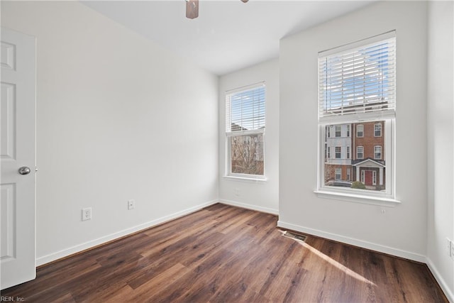 empty room featuring a ceiling fan, baseboards, visible vents, and wood finished floors