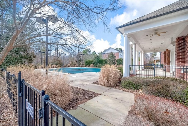 view of swimming pool featuring fence, a ceiling fan, and a covered pool