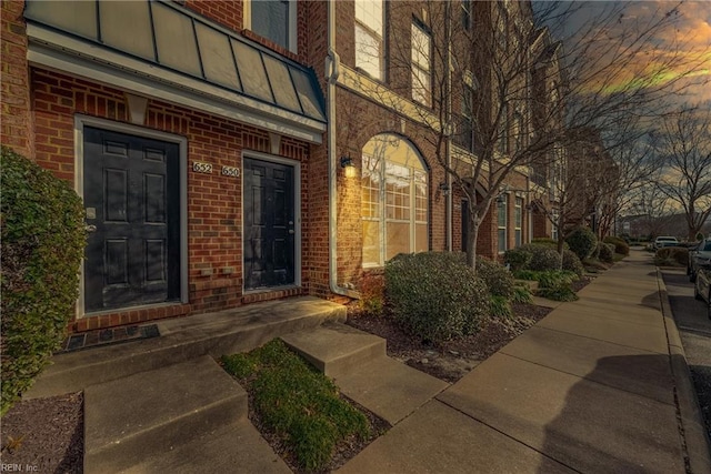 exterior entry at dusk with board and batten siding and brick siding