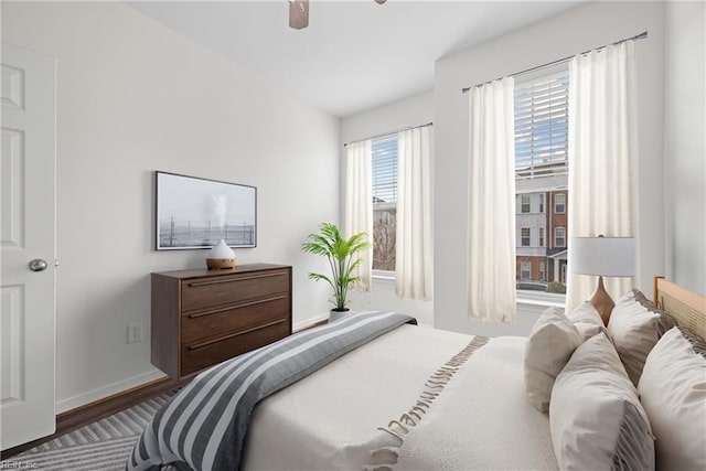 bedroom with a ceiling fan, baseboards, and wood finished floors