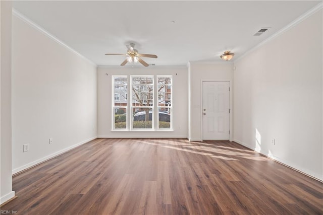 empty room featuring ornamental molding, wood finished floors, visible vents, and baseboards