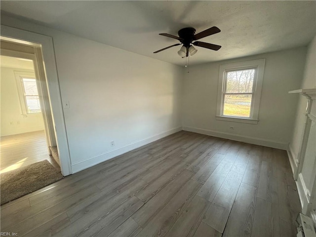 unfurnished room featuring ceiling fan, light wood-type flooring, and a fireplace