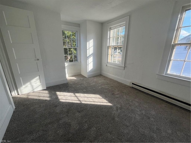 carpeted empty room with a wealth of natural light and a baseboard heating unit