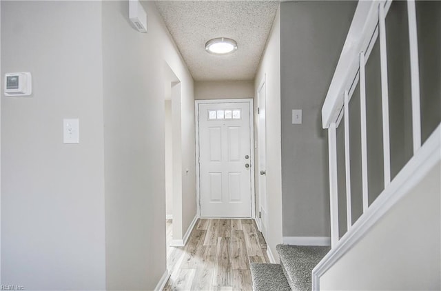 doorway featuring a textured ceiling and light hardwood / wood-style floors