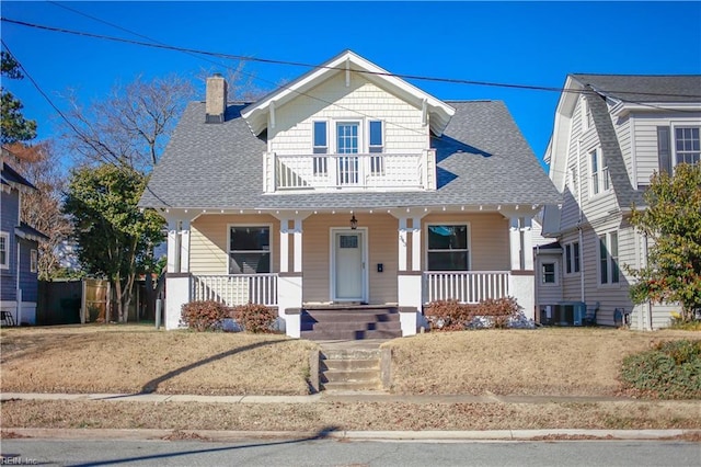 view of front facade with a porch, a balcony, and central AC unit