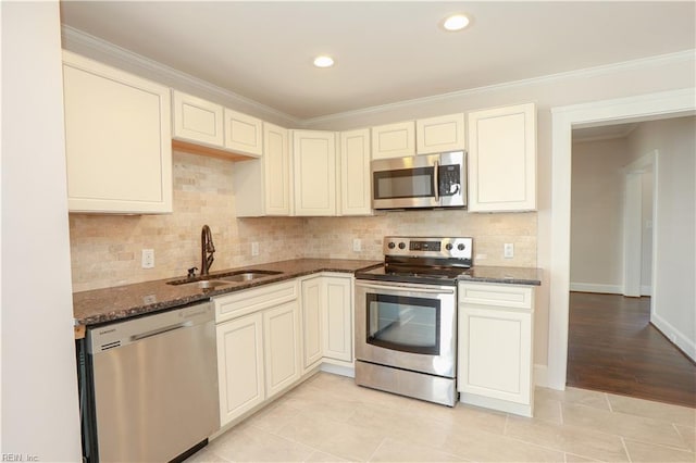 kitchen with light tile patterned floors, sink, appliances with stainless steel finishes, and dark stone counters