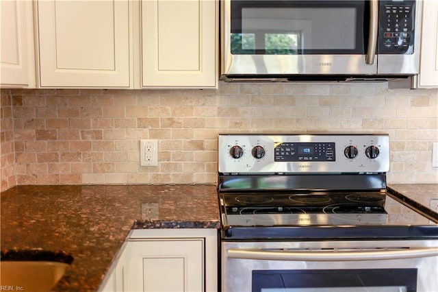 kitchen featuring tasteful backsplash, dark stone countertops, white cabinets, and stainless steel appliances