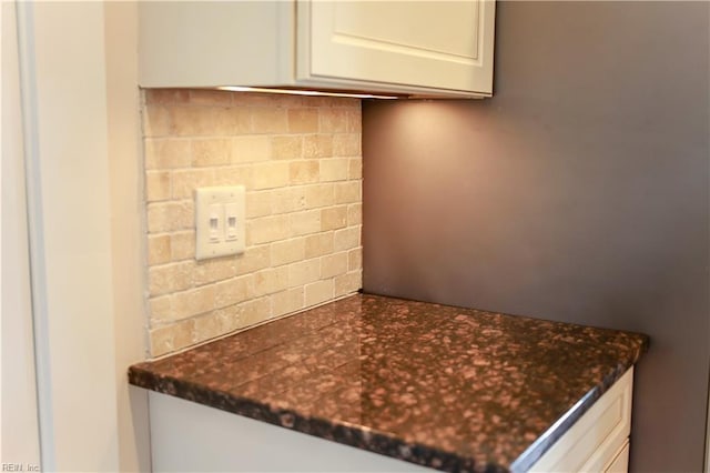 kitchen with decorative backsplash, white cabinets, and dark stone countertops