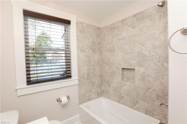 bathroom with toilet and tiled shower / bath