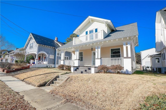 view of front of house featuring covered porch, a balcony, central AC, and a front lawn