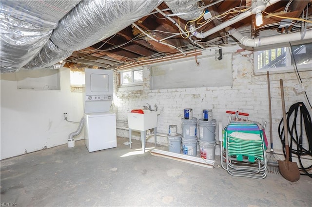 basement with stacked washing maching and dryer and sink