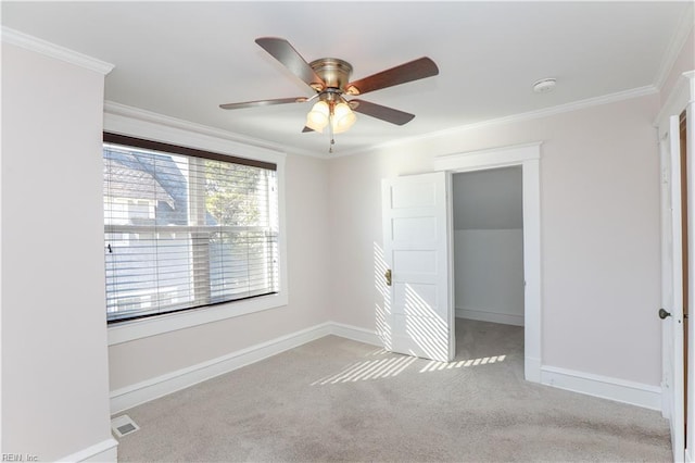 carpeted spare room with crown molding and ceiling fan