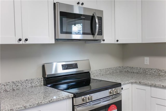 kitchen with white cabinetry, light stone counters, and appliances with stainless steel finishes