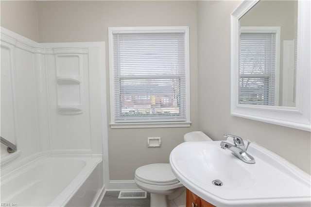 full bathroom with washtub / shower combination, toilet, plenty of natural light, and sink