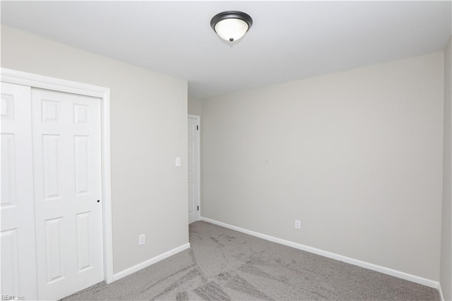 unfurnished bedroom with light colored carpet and a closet