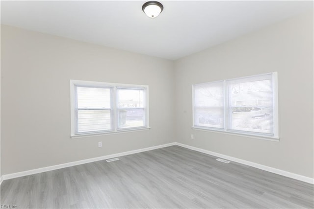 empty room with light hardwood / wood-style flooring and a wealth of natural light