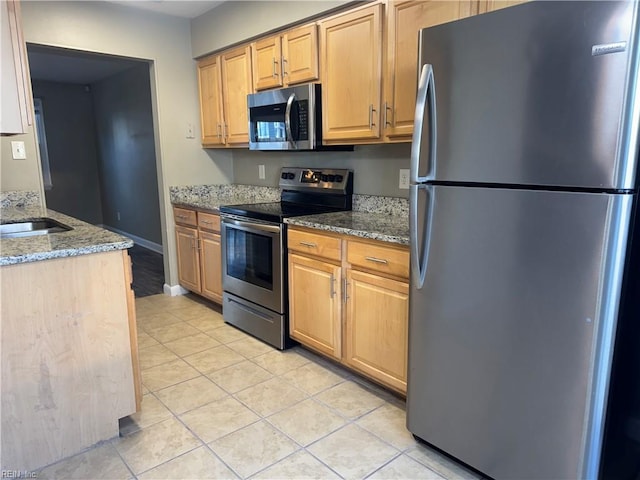 kitchen featuring sink, light stone counters, light tile patterned floors, and stainless steel appliances