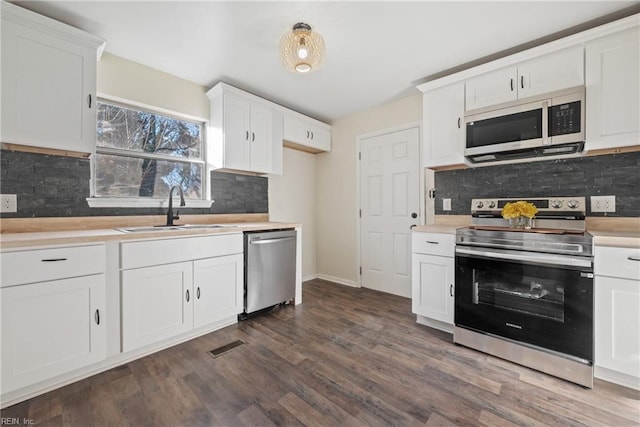 kitchen with decorative backsplash, stainless steel appliances, dark wood-type flooring, sink, and white cabinetry