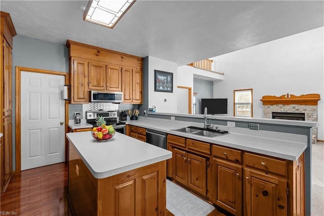 kitchen featuring a center island, sink, stainless steel appliances, decorative backsplash, and a fireplace