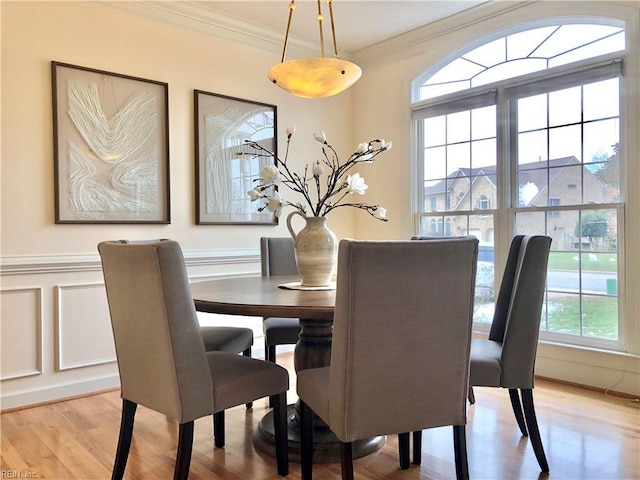 dining space with crown molding and light hardwood / wood-style flooring