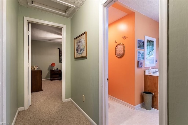 hall featuring light colored carpet and a textured ceiling